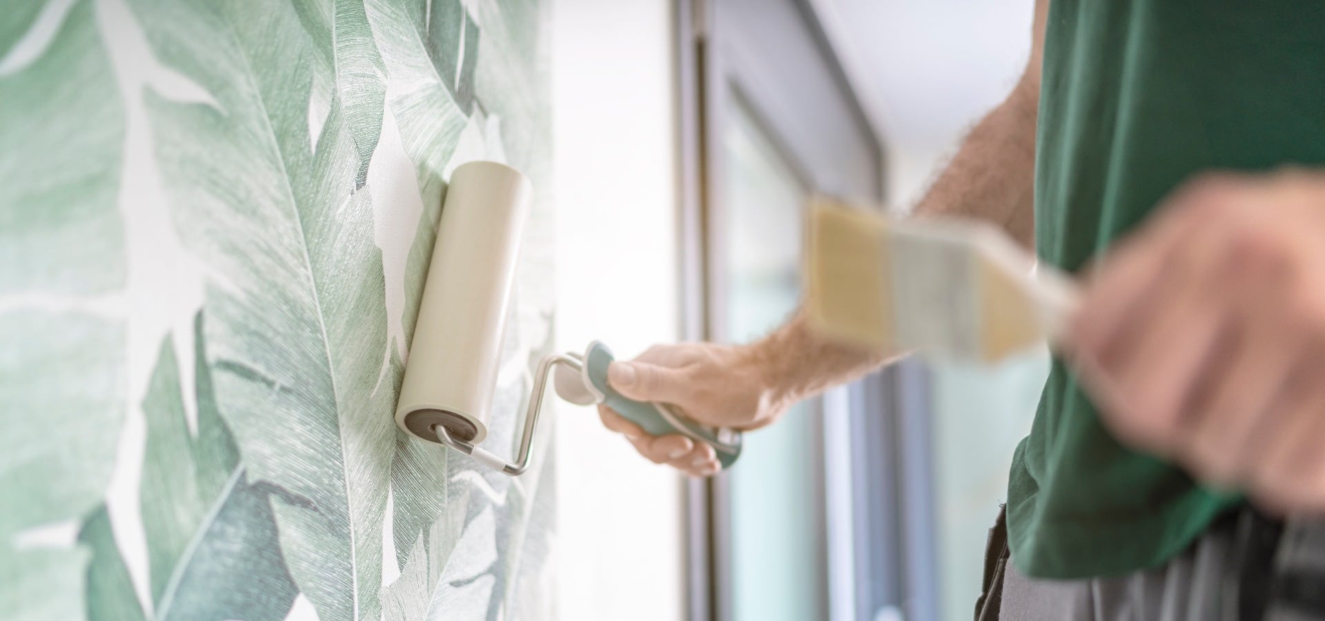 Maler drückt die frisch verklebte Mustertapete mit der Rolle an