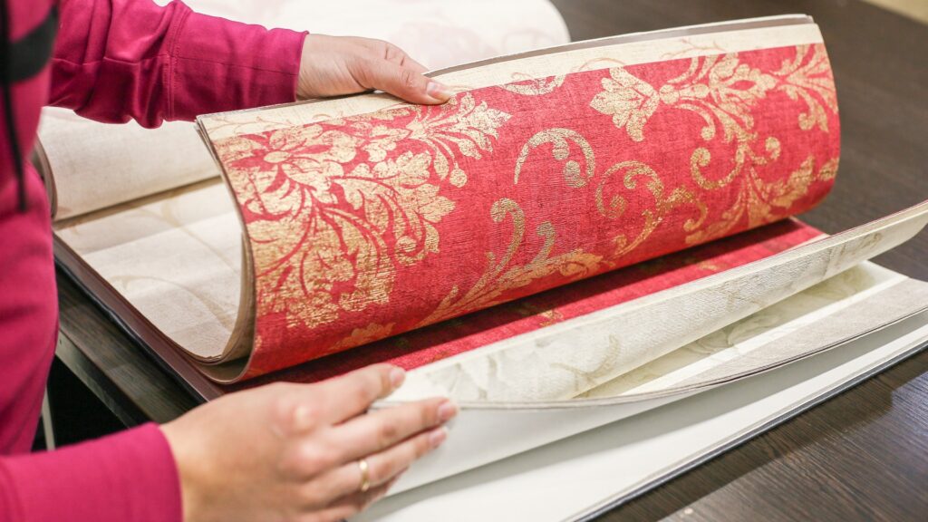 Nahaufnahme einer Frauenhand, die aus dem Tapetenkatalog die passende Farbe für den Raum auswählt